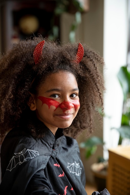 Klein meisje bereidt zich voor op Halloween met een duivelskostuum