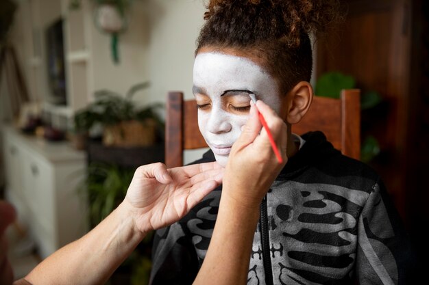 Klein meisje bereidt zich voor op Halloween met een skeletkostuum