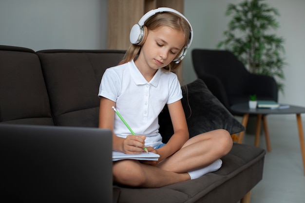 Klein meisje dat deelneemt aan online lessen terwijl ze een koptelefoon gebruikt
