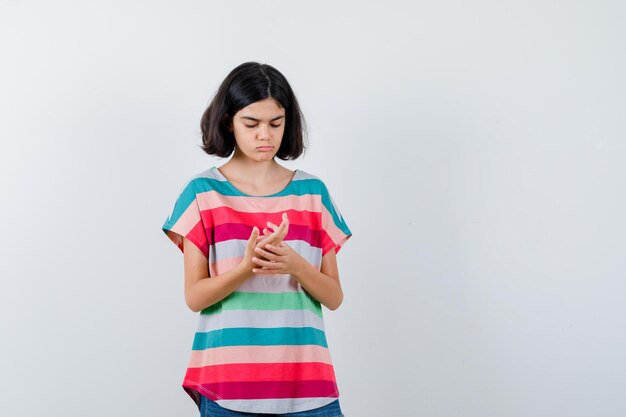 Klein meisje dat naar de palm kijkt als iets in een t-shirt, spijkerbroek en gefocust. vooraanzicht.