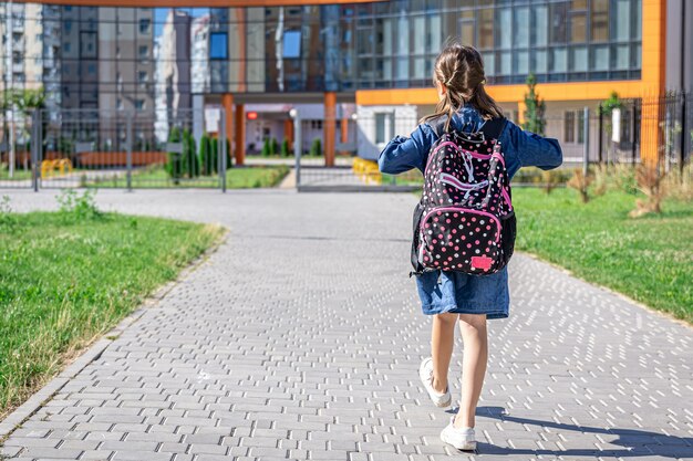 Klein meisje gaat naar de basisschool. Kind met een rugzak gaat studeren. Terug naar schoolconcept.