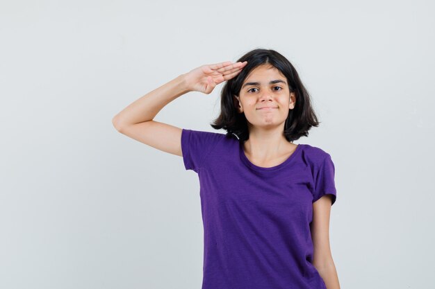 Klein meisje groet gebaar in t-shirt tonen en op zoek zelfverzekerd