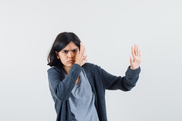 Klein meisje hand in hand om zichzelf te verdedigen in t-shirt, jasje en op zoek angstig