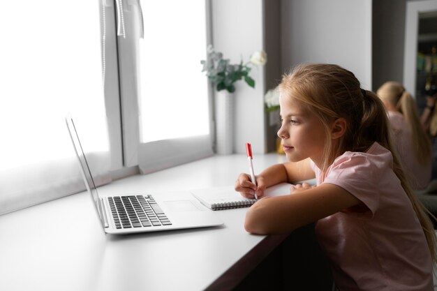 Klein meisje huiswerk thuis met laptop en notebook