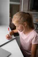 Gratis foto klein meisje huiswerk thuis met laptop en notebook