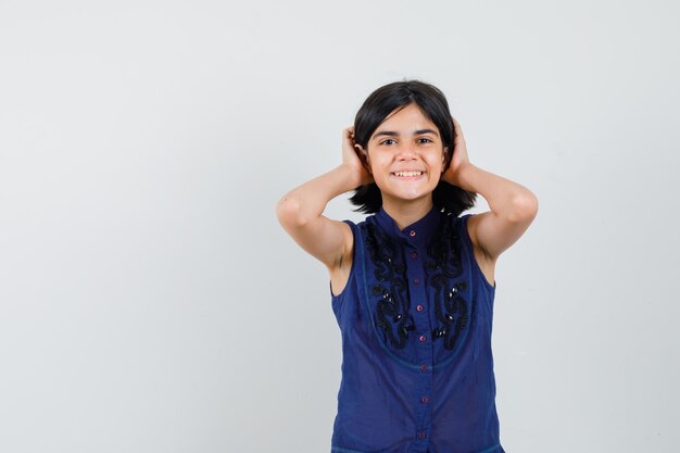 Klein meisje in blauwe blouse hand in hand op haar en op zoek schattig, vooraanzicht.