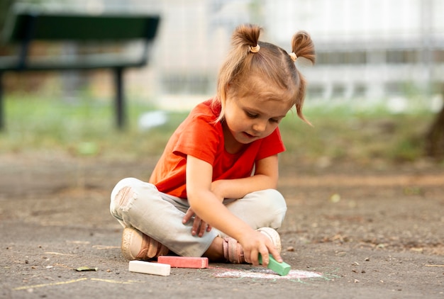 Klein meisje in park tekenen met krijt
