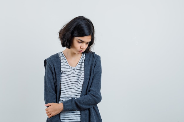 Klein meisje in t-shirt, jas naar beneden te kijken en boos te kijken,