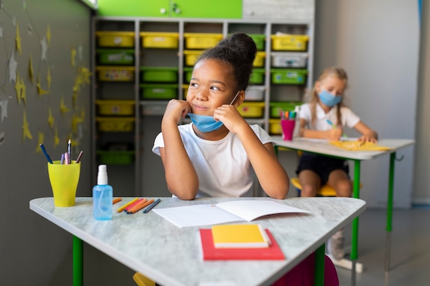 Gratis foto klein meisje lacht tijdens het kijken naar het raam in de klas