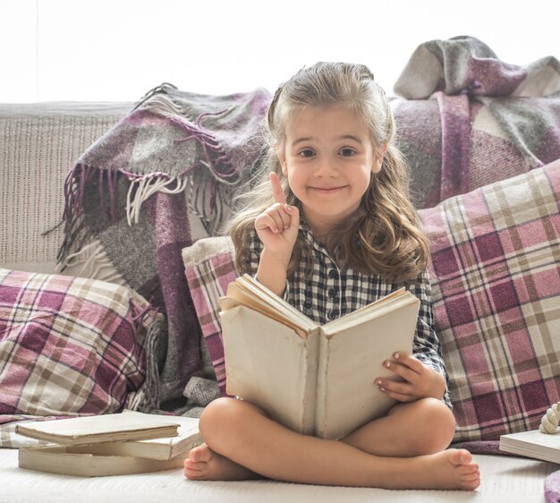 klein meisje leesboek op sofa