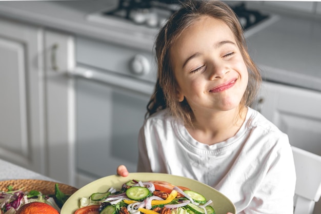 Klein meisje met een bord met verse groentesalade gezond eten concept