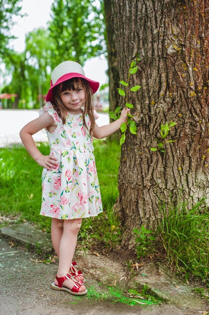 Klein meisje met een hand op een boom leunt