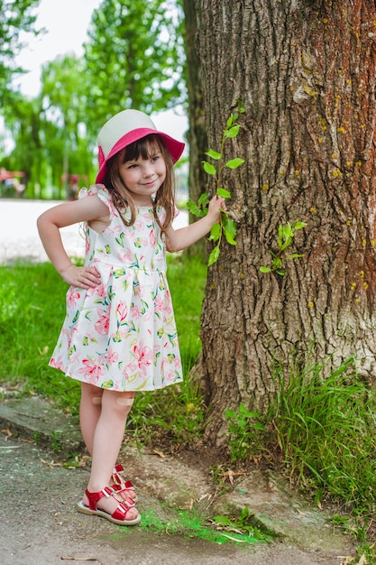 Klein meisje met een hand op een boom leunt