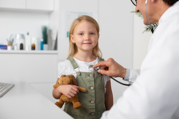 Klein meisje met speelgoed teddybeer op doktersafspraak