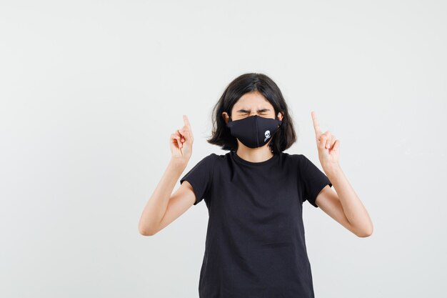 Klein meisje omhoog in zwart t-shirt, masker vooraanzicht.