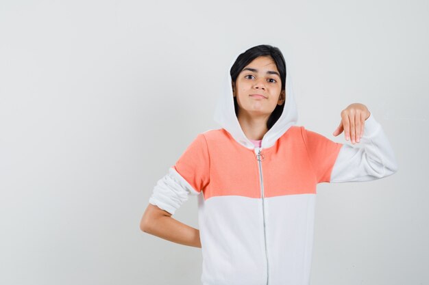 Klein meisje poseren terwijl hand plat in t-shirt, jasje en op zoek zelfverzekerd.