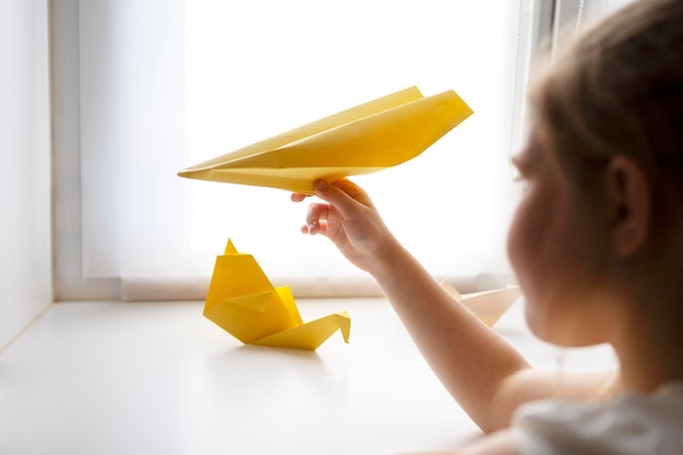 Gratis foto klein meisje speelt thuis met origamipapier