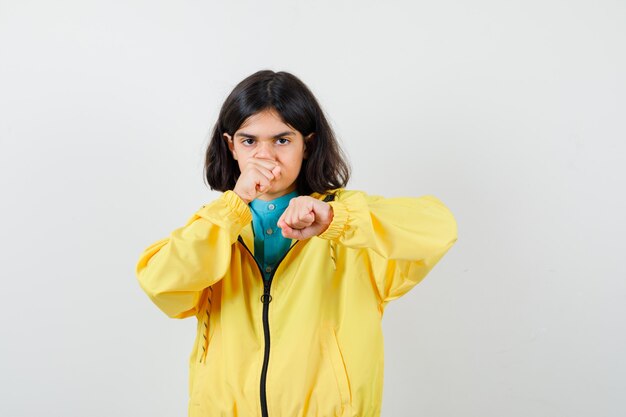 Klein meisje staat in de strijd pose in shirt, jas en ziet er zelfverzekerd uit. vooraanzicht.