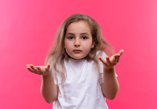 klein schoolmeisje dat wit t-shirt draagt dat welk gebaar op geïsoleerde roze muur toont