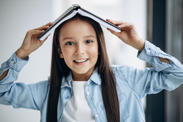 Klein schoolmeisje met boek thuis