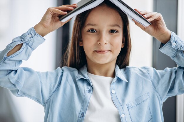 Klein schoolmeisje met boek thuis