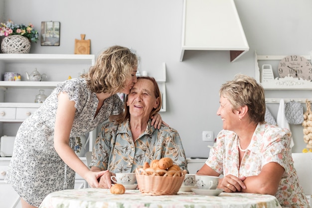 Kleindochter die haar glimlachende oma kust tijdens ontbijt