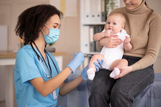 Kleine baby die bij de gezondheidskliniek is voor vaccinatie