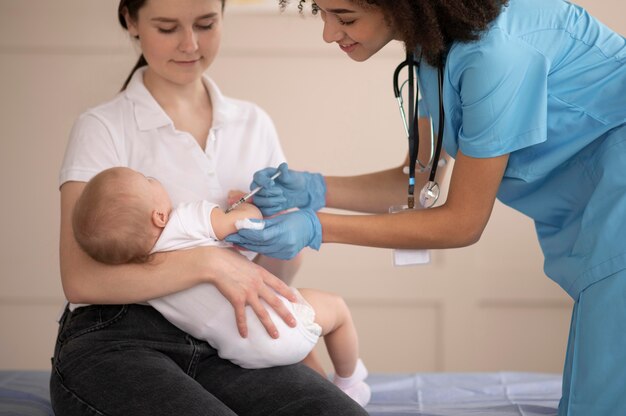 Kleine baby die bij de gezondheidskliniek is voor vaccinatie