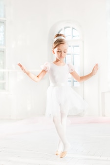 Kleine ballerina meisje in een tutu. aanbiddelijk kind dat klassiek ballet in een witte studio danst.