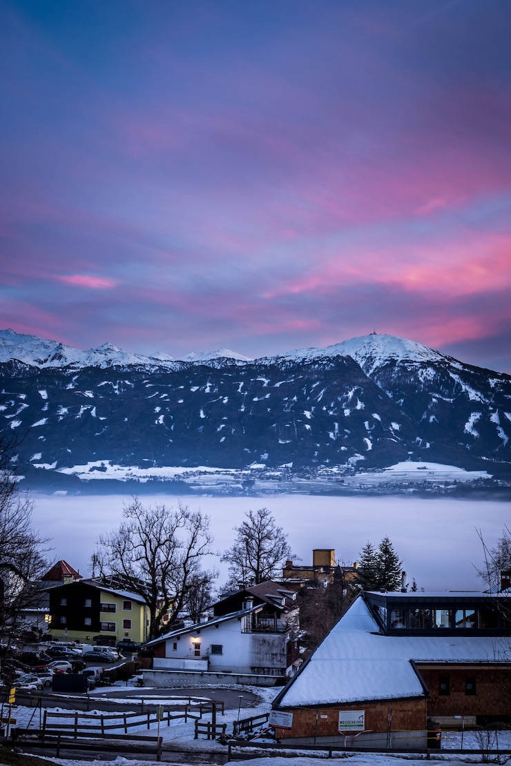 Gratis Foto kleine besneeuwde huizen in een stad met prachtige lucht en bergen