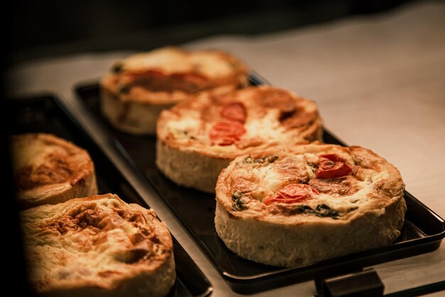 Kleine bladerdeegtaarten met groenten en vleesquiches in een caféraam