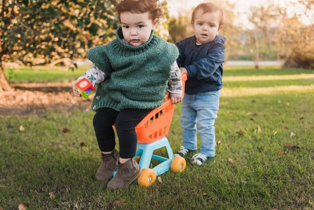 Kleine broer en zus spelen met speelgoedkar in de tuin