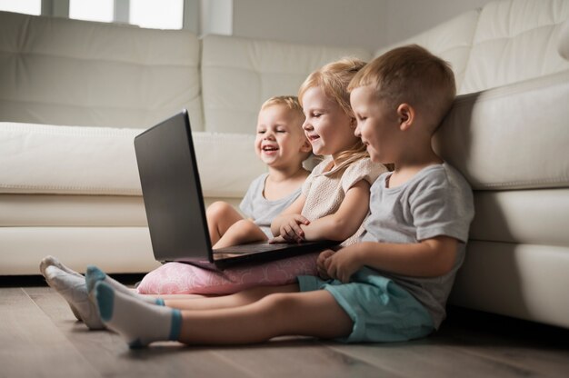 Kleine broer of zus zittend op de vloer en kijken naar laptop