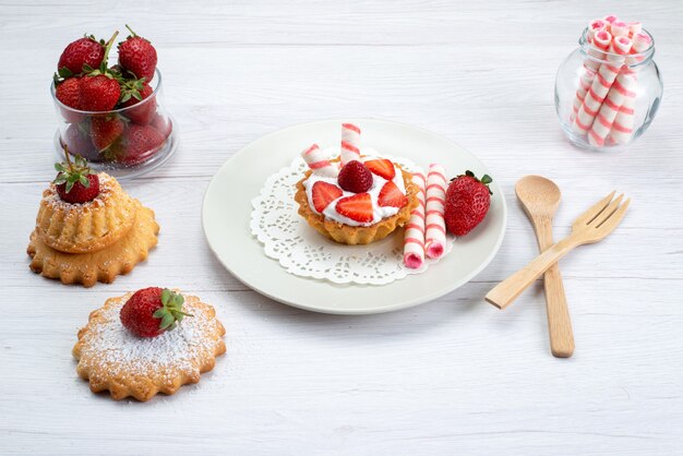 kleine cake met room en gesneden aardbeien taarten snoepjes op wit, fruitcake bessen zoete suiker