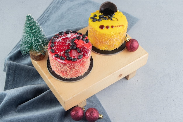Kleine cakes op een bord met kerstversiering op marmeren achtergrond.