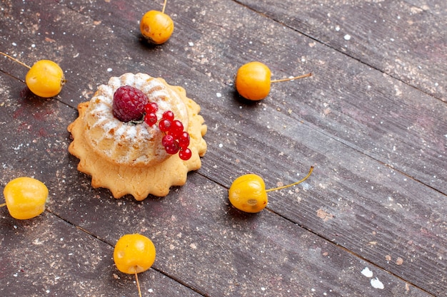 Gratis foto kleine eenvoudige cake met suikerpoeder framboos en veenbessen gele kersen op bruin houten rustiek, bessen fruit cake zoete bak