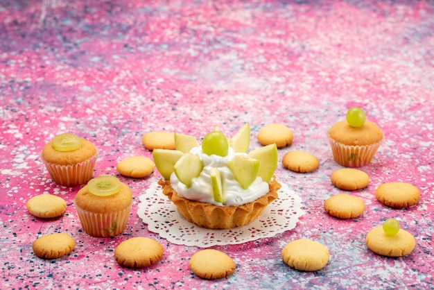 kleine heerlijke cake met gesneden fruitkoekjes op gekleurd bureau, cake zoete suiker kleurenfoto