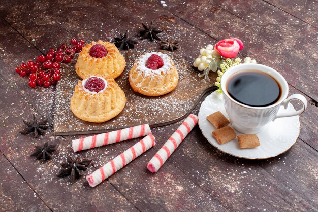 kleine heerlijke cakes met frambozen en veenbessen samen met stoksuikergoed Koffie op houten bureau, cake zoet fruit bak biscuit bes