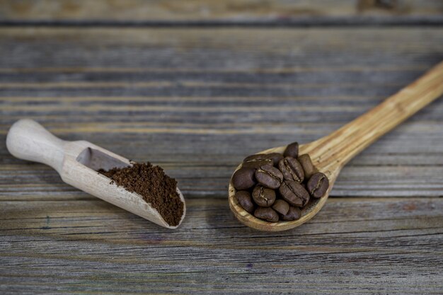 Kleine houten lepels met koffiebonen en koffiepoeder