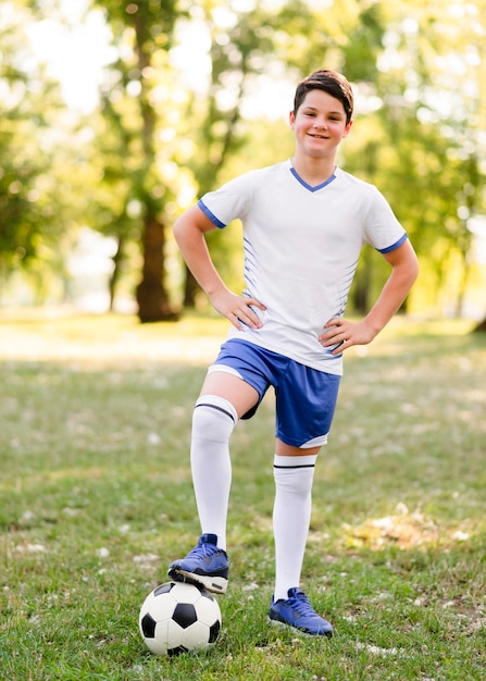 Kleine jongen buiten poseren met een voetbal