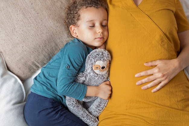 Gratis foto kleine jongen die naast zijn moeder slaapt