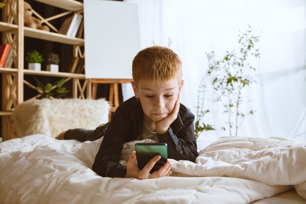 Kleine jongen die thuis verschillende gadgets gebruikt