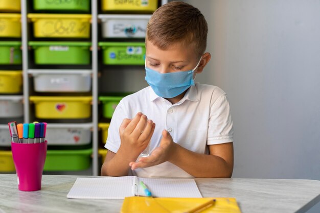 Kleine jongen die zijn handen desinfecteert