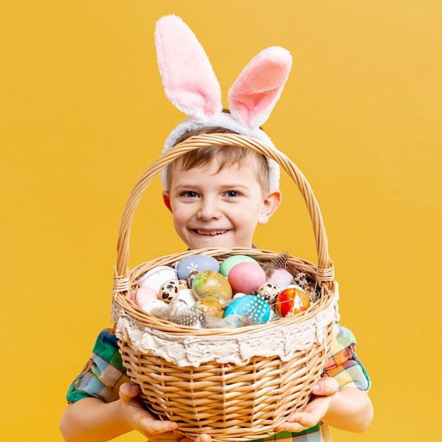 Gratis foto kleine jongen houden mand met beschilderde eieren