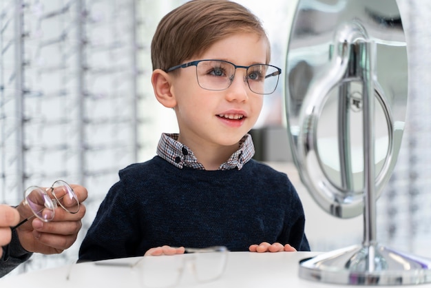 Kleine jongen in de winkel die op een bril probeert