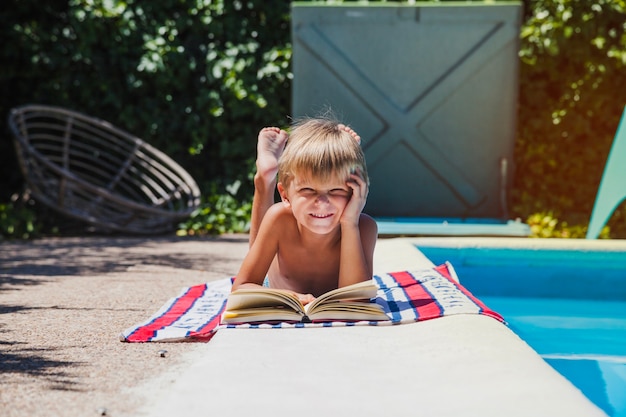 Gratis foto kleine jongen liggend op handdoek bij het zwembad