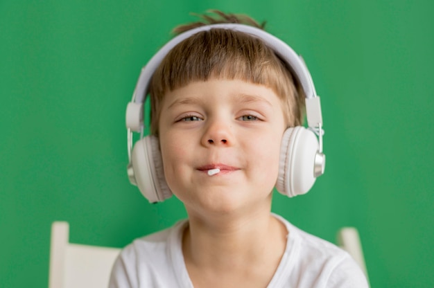 Kleine jongen met koptelefoon eten lollipop