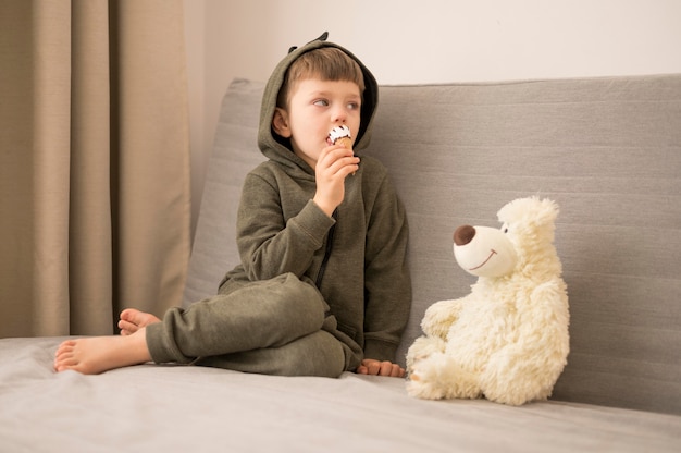 Gratis foto kleine jongen met tedy beer op de bank