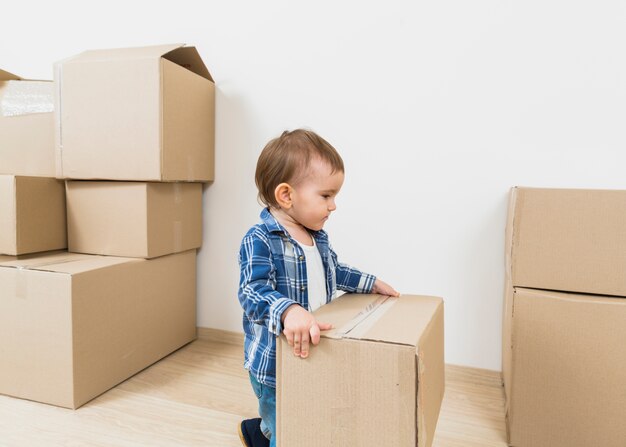 Kleine jongen peuter houden kartonnen doos in zijn nieuwe huis