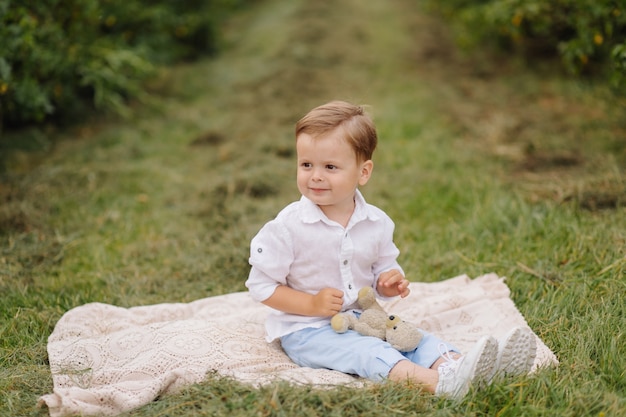 Kleine jongen zittend op picknick plaid in cottage tuin